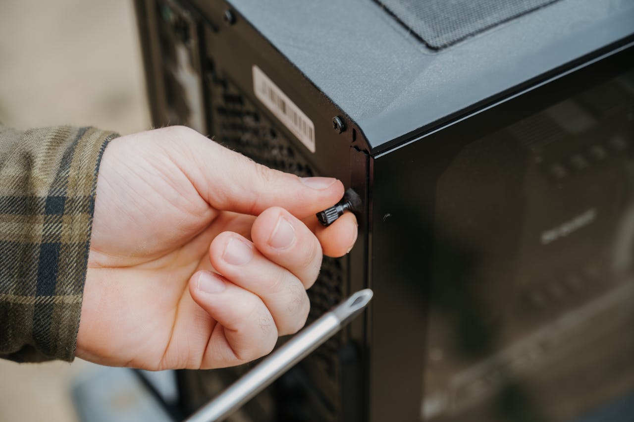 about-01 Close-up of a hand unscrewing a desktop computer case, emphasizing technology maintenance.