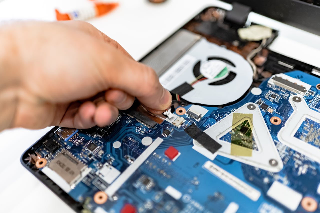 gallery-1 Close-up view of a hand fixing a computer motherboard showcasing technology and electronics repair.